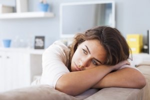 Sad woman with low confidence sits on couch