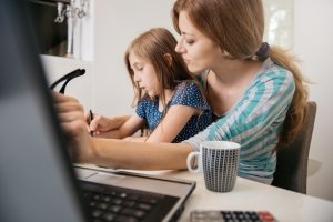 Single mom working at home in the kitchen with daughter